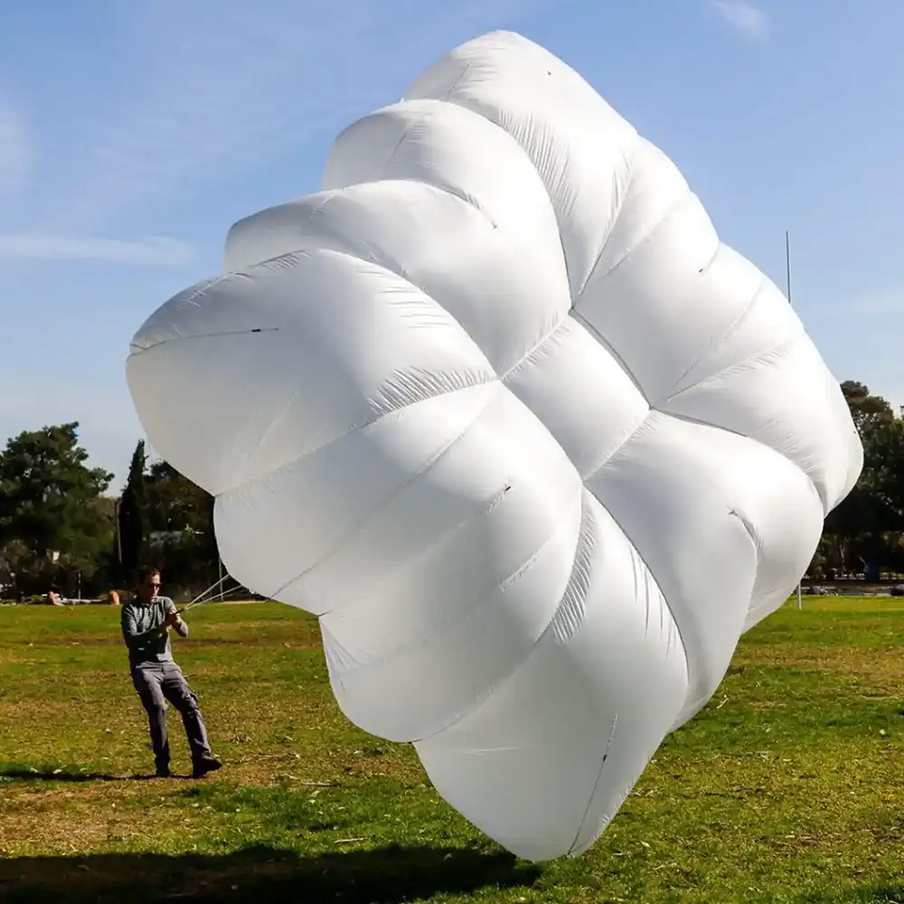 Campana rectangular blanca hinchada en el suelo, sujeta por una persona sobre el césped