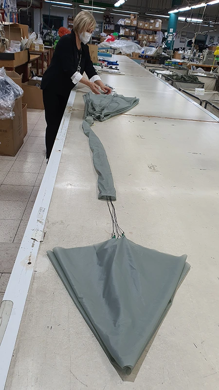 Operario extendiendo un velamen gris verdoso sobre una larga mesa de plegado