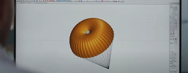 Modelo 3D de un velamen redondo con sus suspentes en un programa de diseño, en un monitor