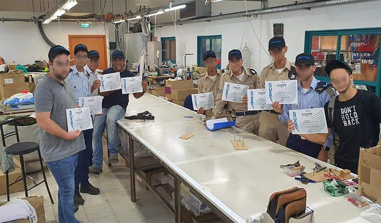 Partecipanti a un corso di ripiegatura con gli attestati in mano in un capannone di produzione