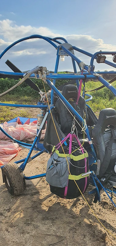 Telaio di paracarrello blu con un contenitore del paracadute fissato e, accanto, una velatura distesa sul campo