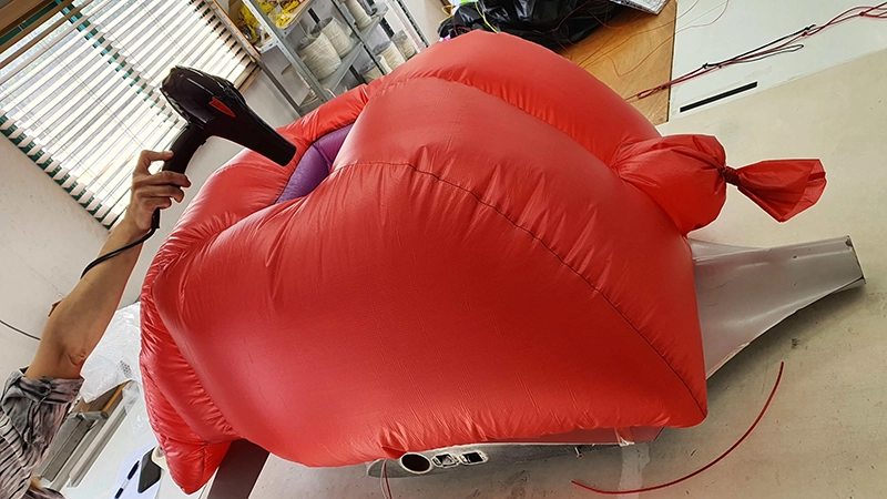 Elemento gonfiabile ultraleggero rosso gonfiato con un soffiatore su un banco da lavoro