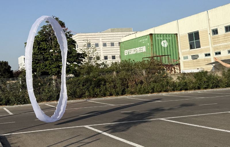 Weiße ringförmige Kappe steht aufrecht auf einem Betonplatz, die Mitte bleibt offen