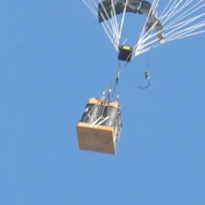 Carga con un absorbedor de impacto en su cara inferior descendiendo bajo un paracaídas