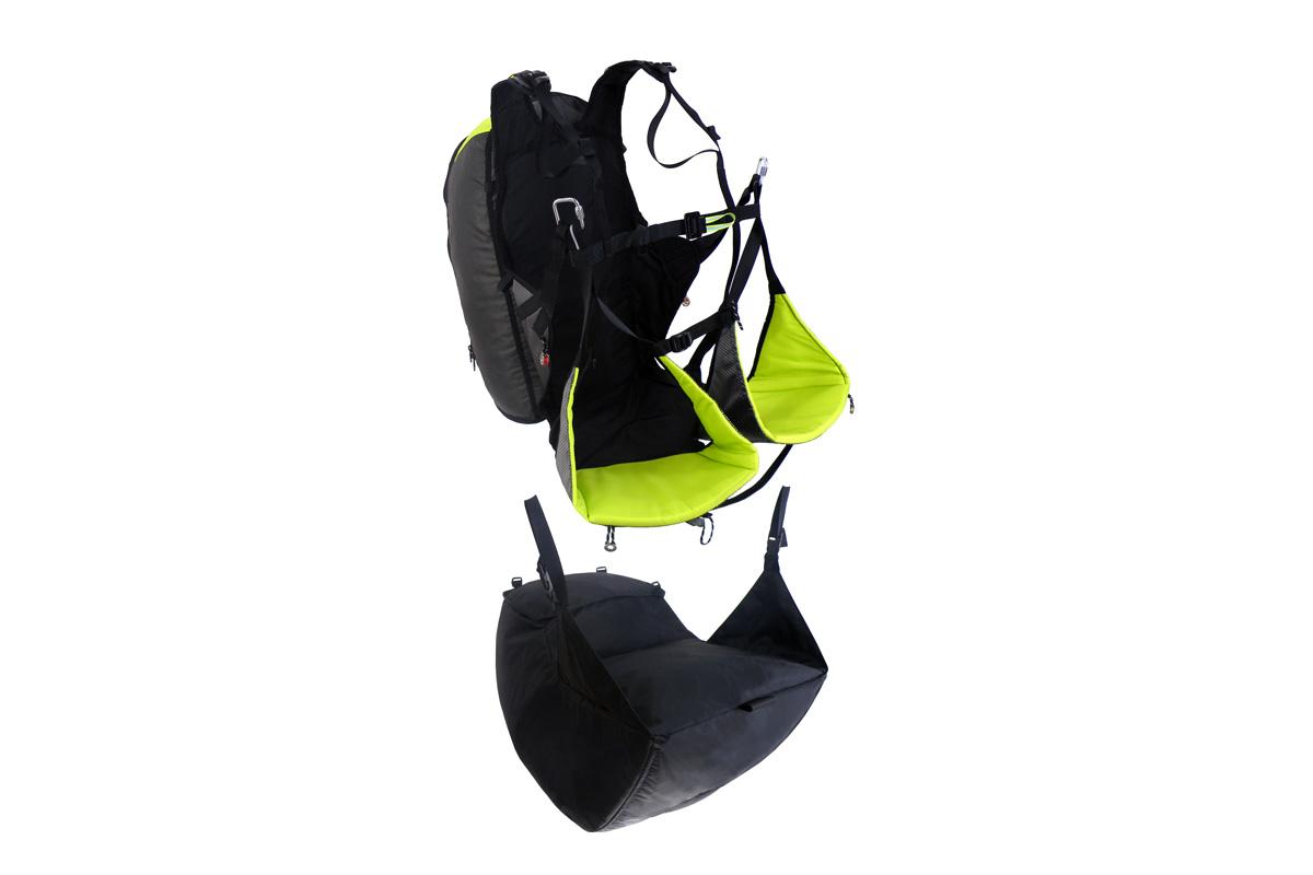 Imbracatura da parapendio scontornata con seduta verde lime e, sotto, l'elemento airbag nero staccato