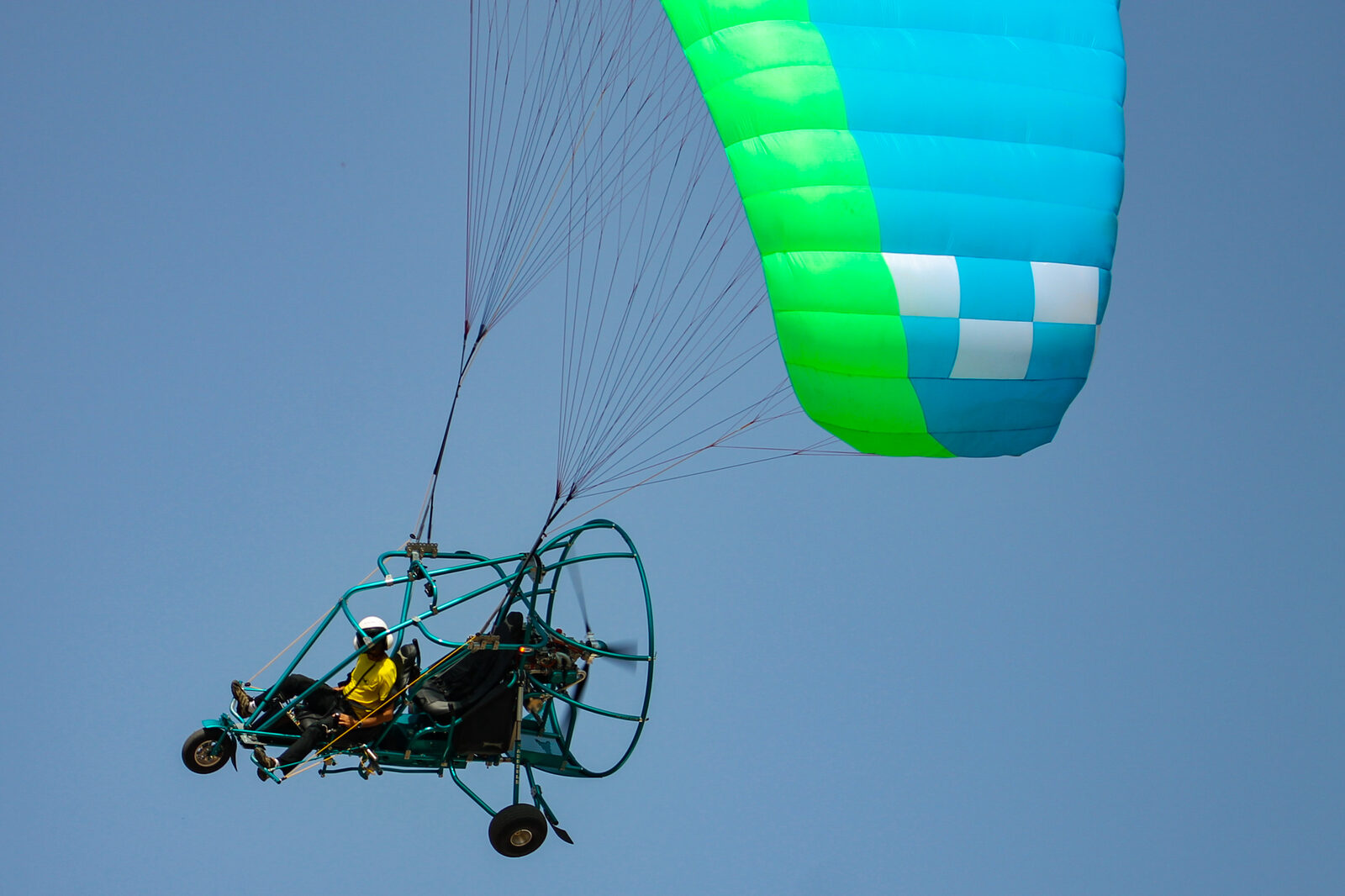 Vista lateral de un trike en vuelo, con ambas bandas subiendo desde los anclajes de la estructura hasta la vela